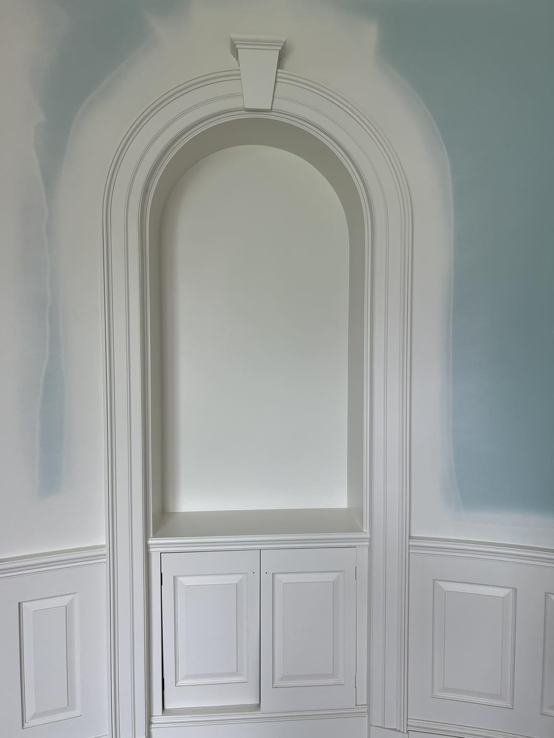 Custom arched wall niche with decorative trim and lower built-in cabinetry by Ruach Custom Carpentry in Columbus, Ohio, featuring detailed wainscoting, intricate molding, and precision finish carpentry. This custom carpentry project highlights expert woodwork and classic architectural detailing, creating a timeless and elegant feature in a luxury Central Ohio home.