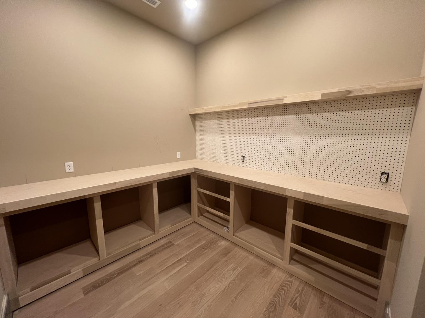 Custom built-in woodworking workshop featuring natural wood cabinetry, open shelving, integrated pegboard wall, and durable hardwood flooring, designed and crafted by Ruach Custom Carpentry.