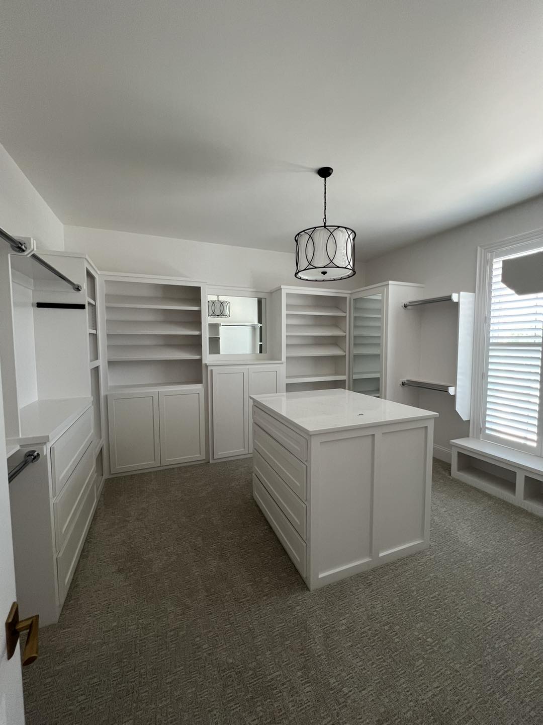 Custom walk-in closet installation by Ruach Custom Carpentry in Columbus, Ohio, featuring built-in shelving, drawers, hanging space, a center island with storage, and a window bench seat. This luxury carpentry project showcases expert finish carpentry, custom closet design, and precision craftsmanship, creating a beautifully organized, high-end dressing space for a Central Ohio home.