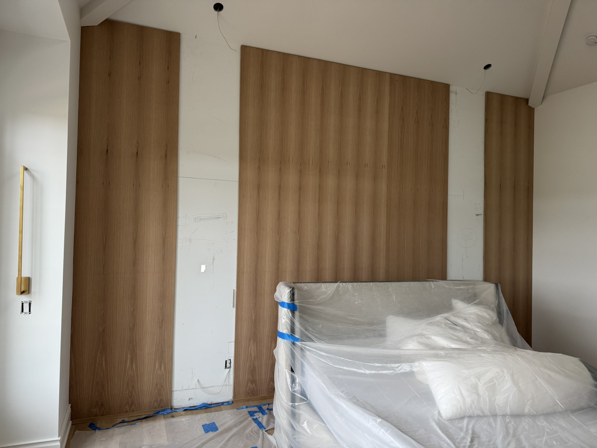 Custom white oak wall paneling installation behind bed area, designed and built by Ruach Custom Carpentry. The natural oak wood adds warmth, texture, and a modern architectural focal point to the bedroom space.