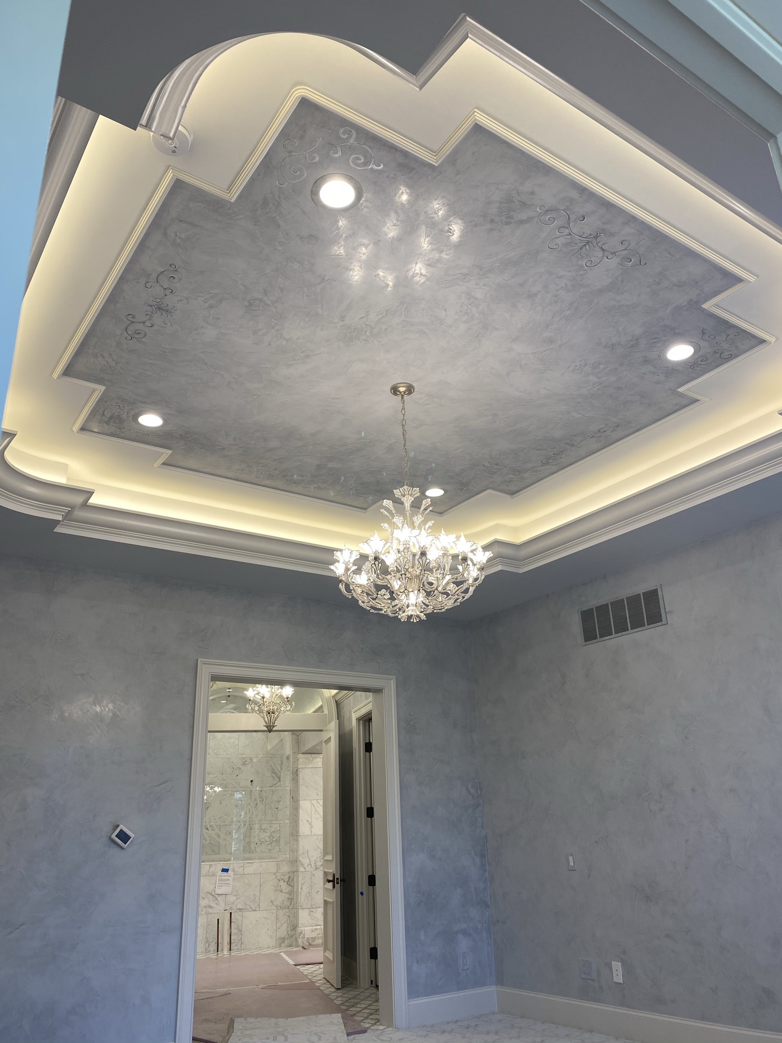 Custom coffered ceiling trim and detailed crown molding installation by Ruach Custom Carpentry in Columbus, Ohio, featuring a luxury multi-tiered tray ceiling with ambient lighting, intricate trim accents, and a decorative chandelier centerpiece. This custom carpentry project showcases expert finish carpentry, custom millwork, and precision trim craftsmanship, elevating the architectural elegance of a luxury Central Ohio home.