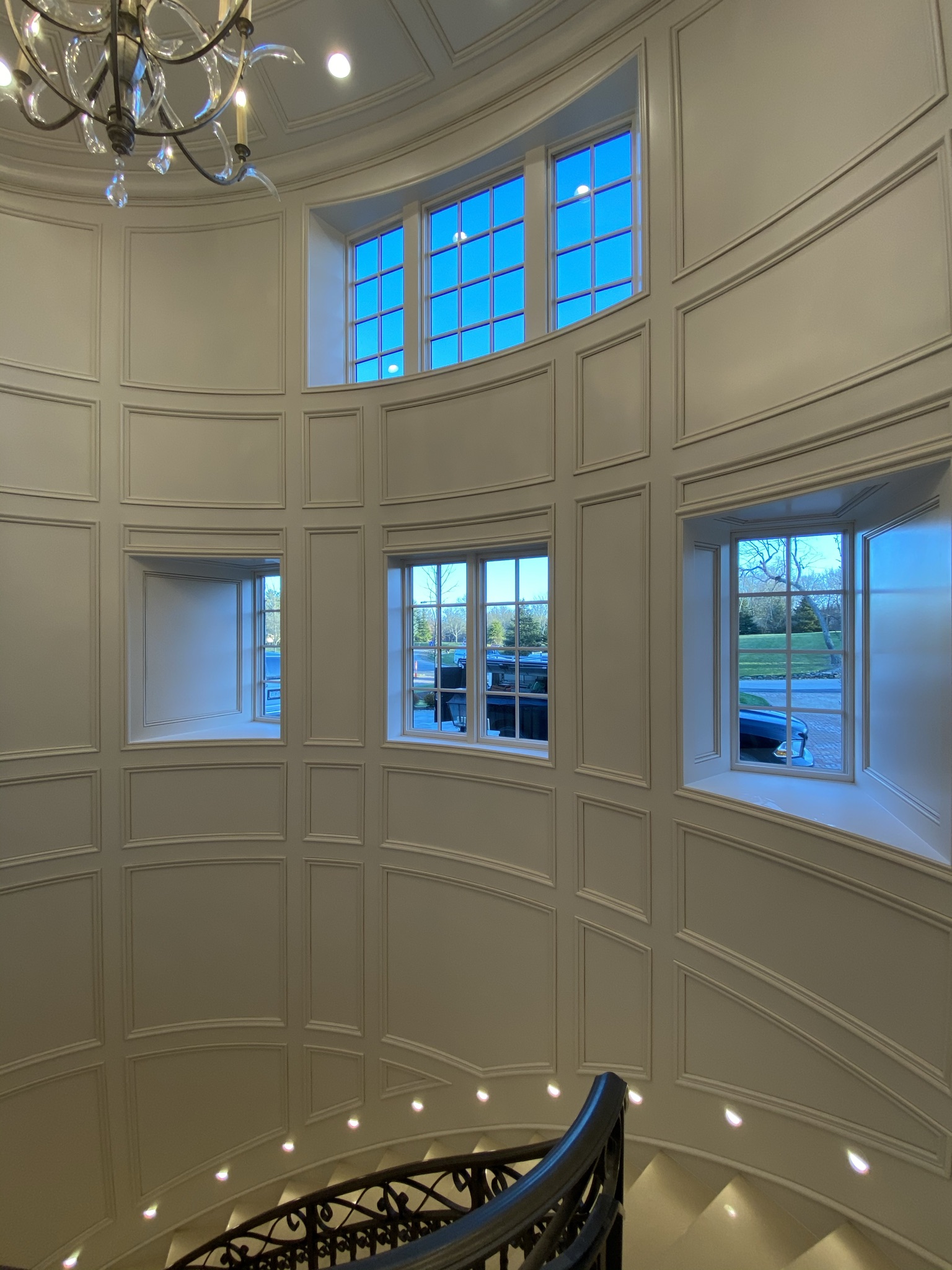 Custom curved wall paneling and detailed trim carpentry installation by Ruach Custom Carpentry in Columbus, Ohio, featuring elegant handcrafted wood paneling on a grand staircase with arched windows and intricate trim work. This luxury custom carpentry project highlights expert finish carpentry, custom millwork, and precision craftsmanship, creating a stunning architectural feature in a high-end Central Ohio home.