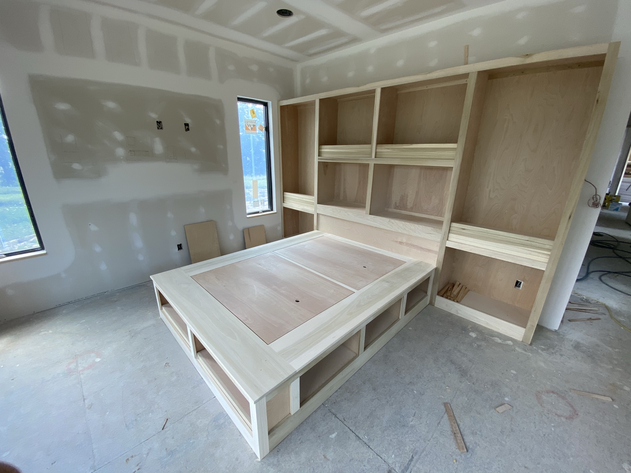 Custom built-in bed base with integrated headboard shelving and under-bed storage by Ruach Custom Carpentry in Columbus, Ohio. This handcrafted bed features a large wood headboard with open shelving for books and decor, combined with spacious under-bed compartments for functional storage. Designed to maximize space while showcasing expert finish carpentry, precision craftsmanship, and creative woodwork solutions for custom bedrooms in Central Ohio.