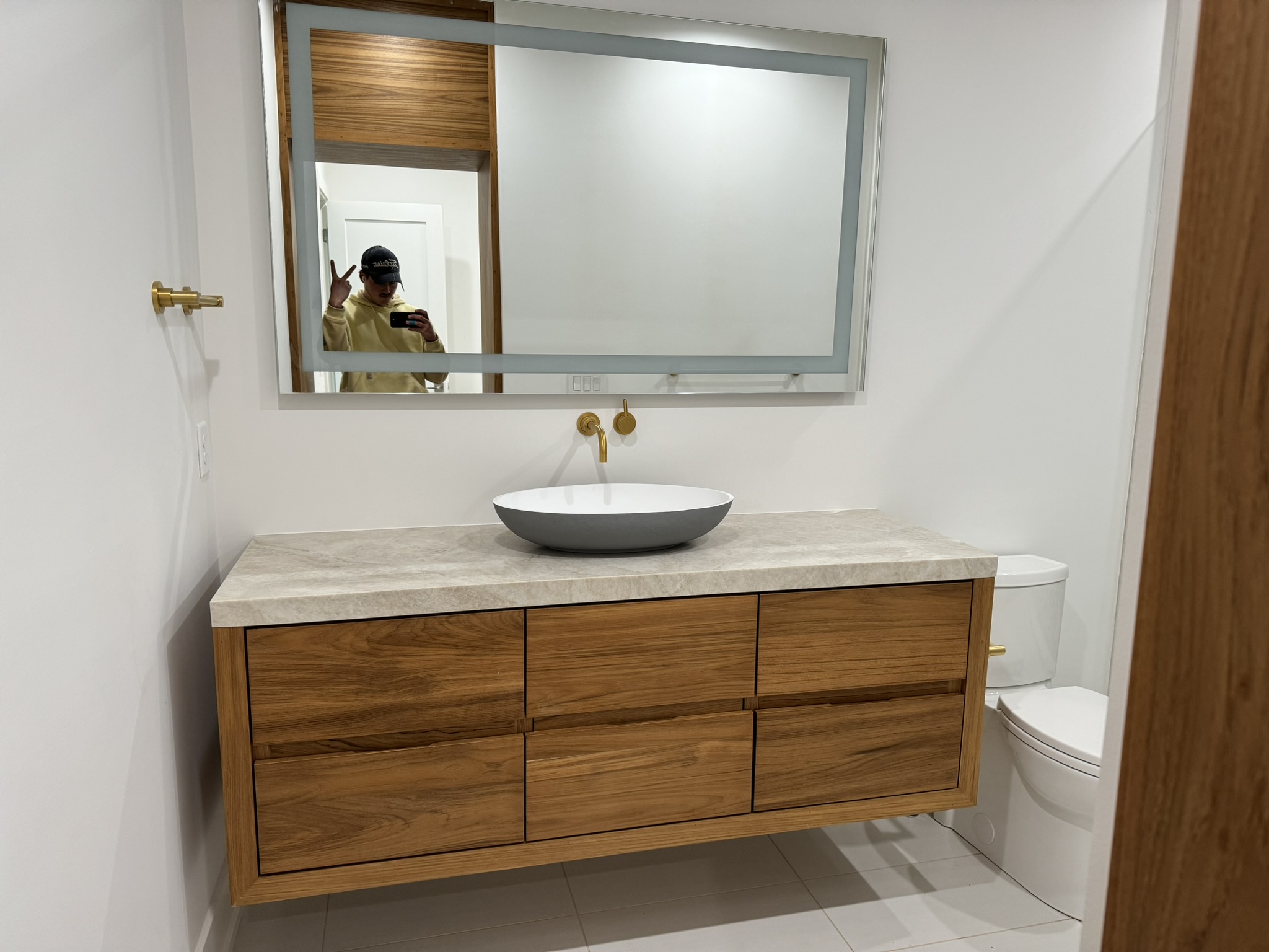 Custom floating bathroom vanity handcrafted by Ruach Custom Carpentry, featuring a natural wood finish, sleek flat-panel drawers, a modern vessel sink, and a stone countertop. This high-end vanity design combines minimalist style and expert craftsmanship, perfect for luxury bathroom renovations in Columbus, Ohio.