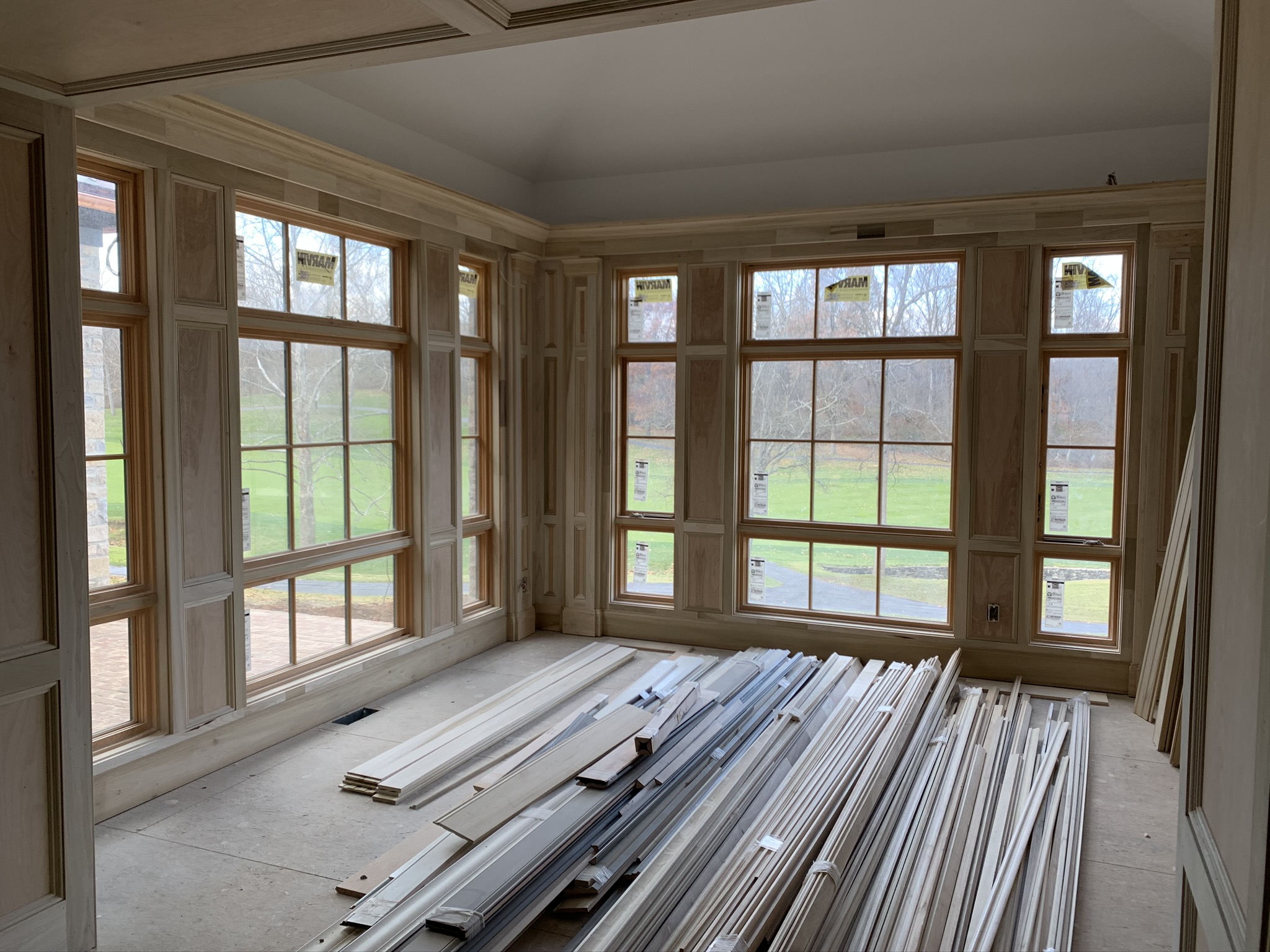 Custom floor-to-ceiling wood trim and wall paneling surrounding large picture windows, handcrafted by Ruach Custom Carpentry in Columbus, Ohio. This bright and elegant sunroom showcases detailed millwork, expert trim installation, and precision craftsmanship to frame expansive views and add architectural beauty. Perfect example of custom interior woodwork, finish carpentry, and luxury home detailing in Central Ohio.