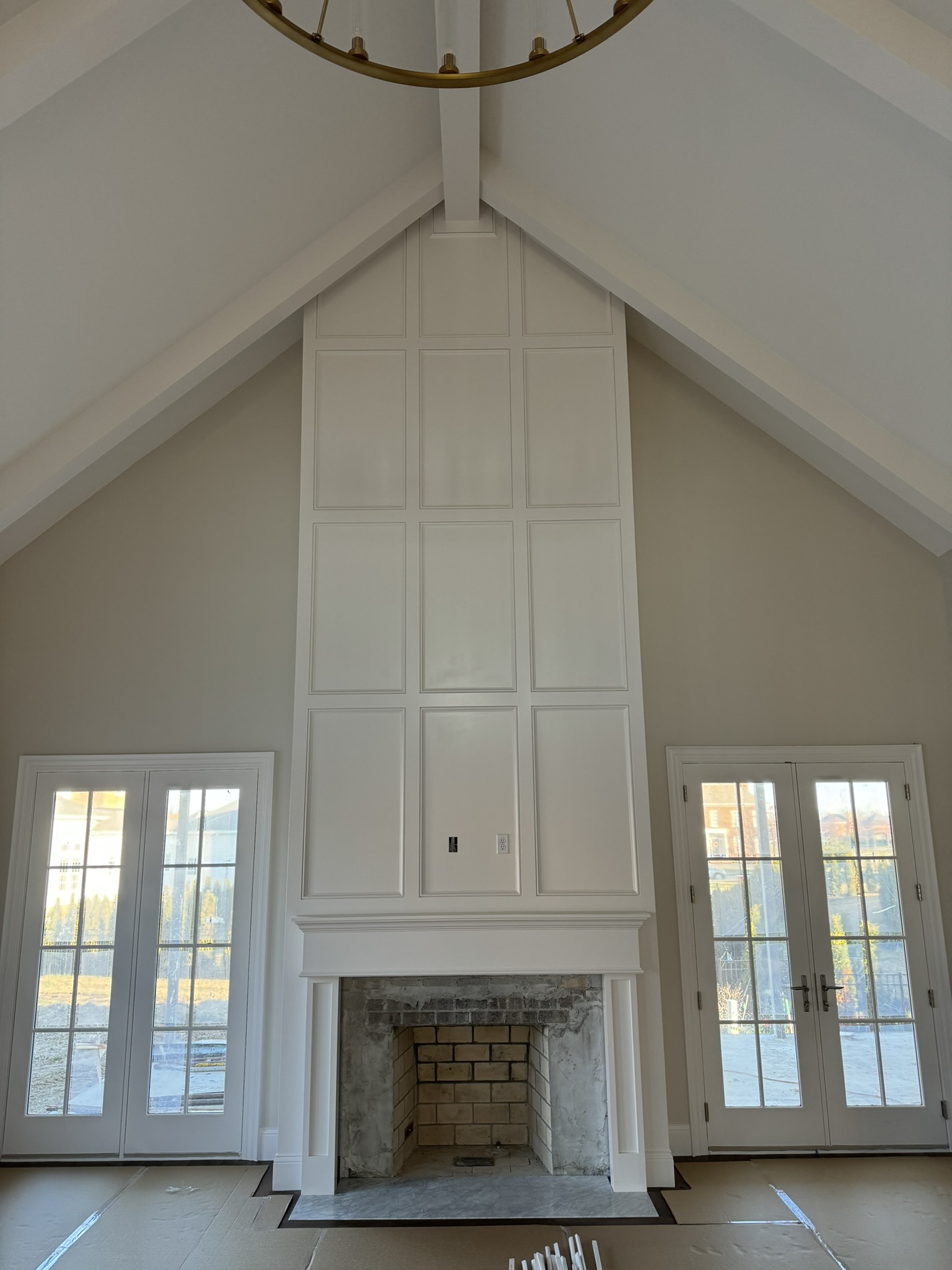 Custom floor-to-ceiling fireplace wall with detailed panel molding, created by Ruach Custom Carpentry. Featuring a vaulted ceiling design, elegant millwork, and a spacious traditional fireplace surround, this statement piece brings timeless craftsmanship and luxury to this Columbus, Ohio home.