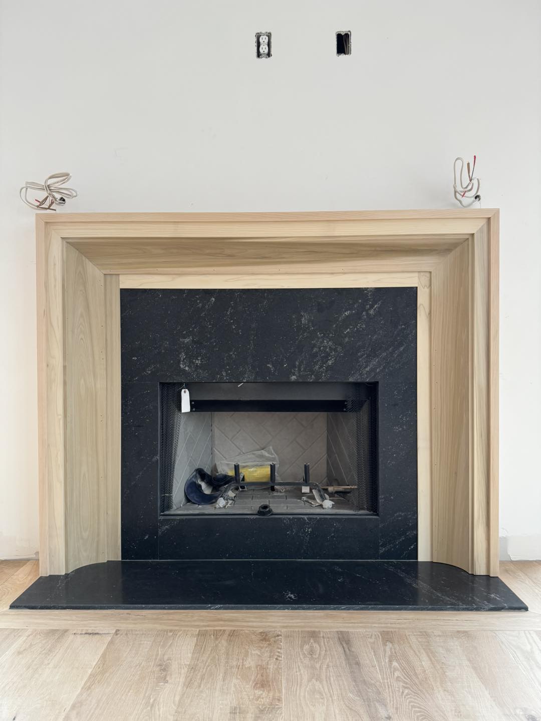 Custom wood fireplace mantel crafted by Ruach Custom Carpentry in Columbus, Ohio, featuring a modern natural wood surround framing a black stone fireplace with elegant clean lines. This custom carpentry project highlights expert finish carpentry, custom mantel design, and precision woodwork, creating a stunning focal point for a luxury residential living space in Central Ohio.