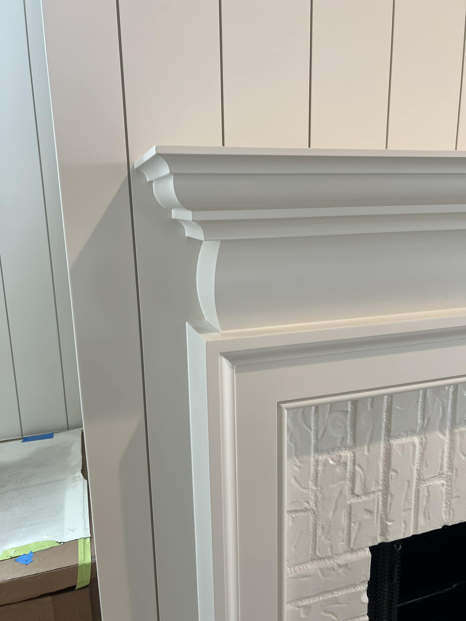 Detailed custom wood fireplace mantel and trim work by Ruach Custom Carpentry in Columbus, Ohio, featuring elegant crown molding, vertical shiplap wall paneling, and a painted brick fireplace surround. This custom carpentry project highlights precision finish carpentry, traditional mantel design, and expert craftsmanship, adding timeless architectural character to a luxury home in Central Ohio.